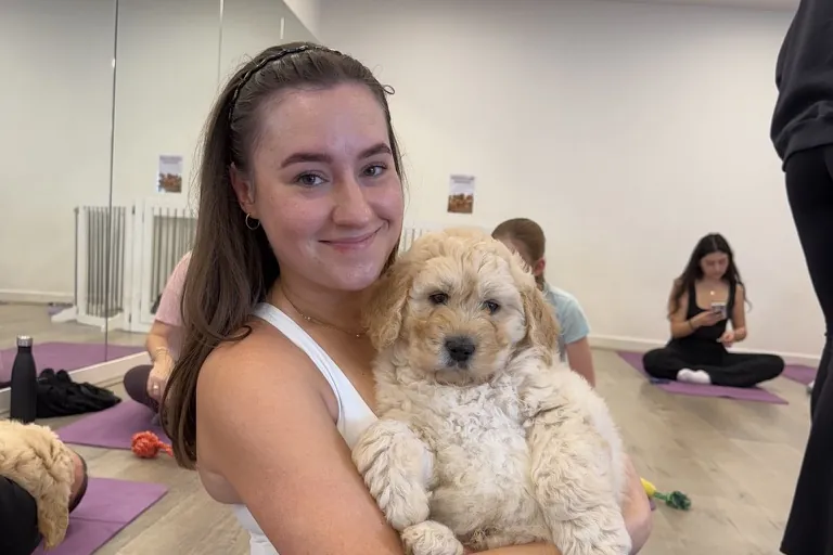 A guest holding a fluffy puppy at a Yoga Paws session